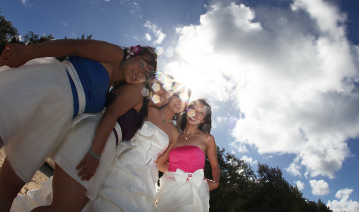 bridesmaids with a smile while the sunshines through the clouds in hawaii on the sandy shore